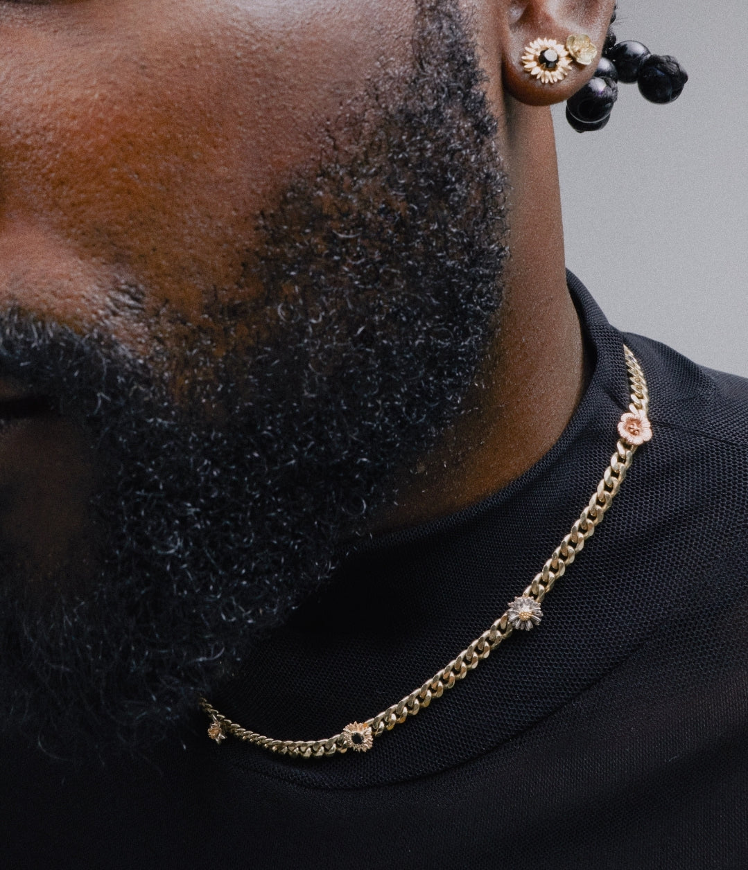 Man wearing a yellow gold curb necklace with flower appliques