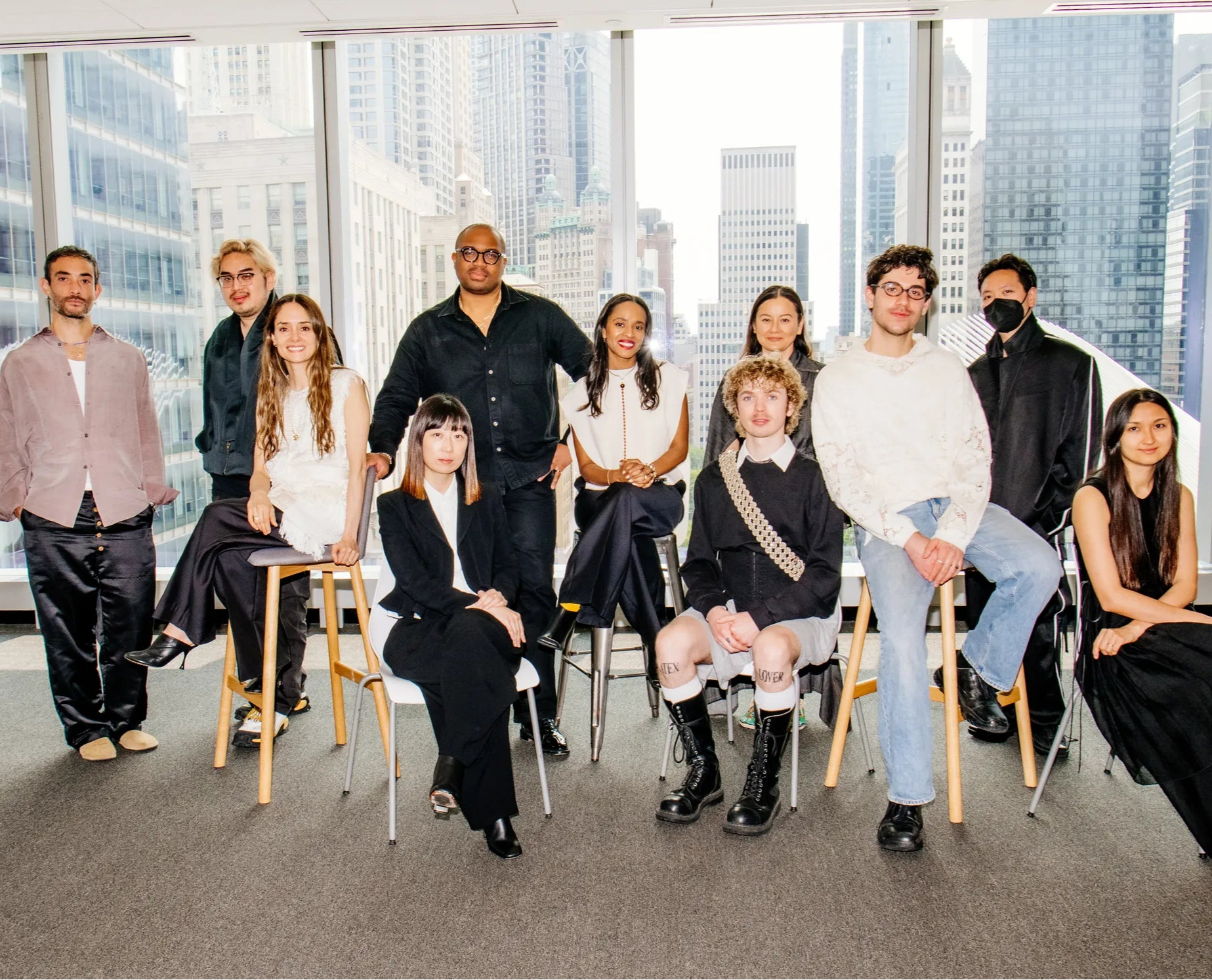 Group of people sitting in chairs in a modern office setting with cityscape view.