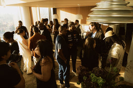 Group of people gathered in a modern indoor setting with large windows.