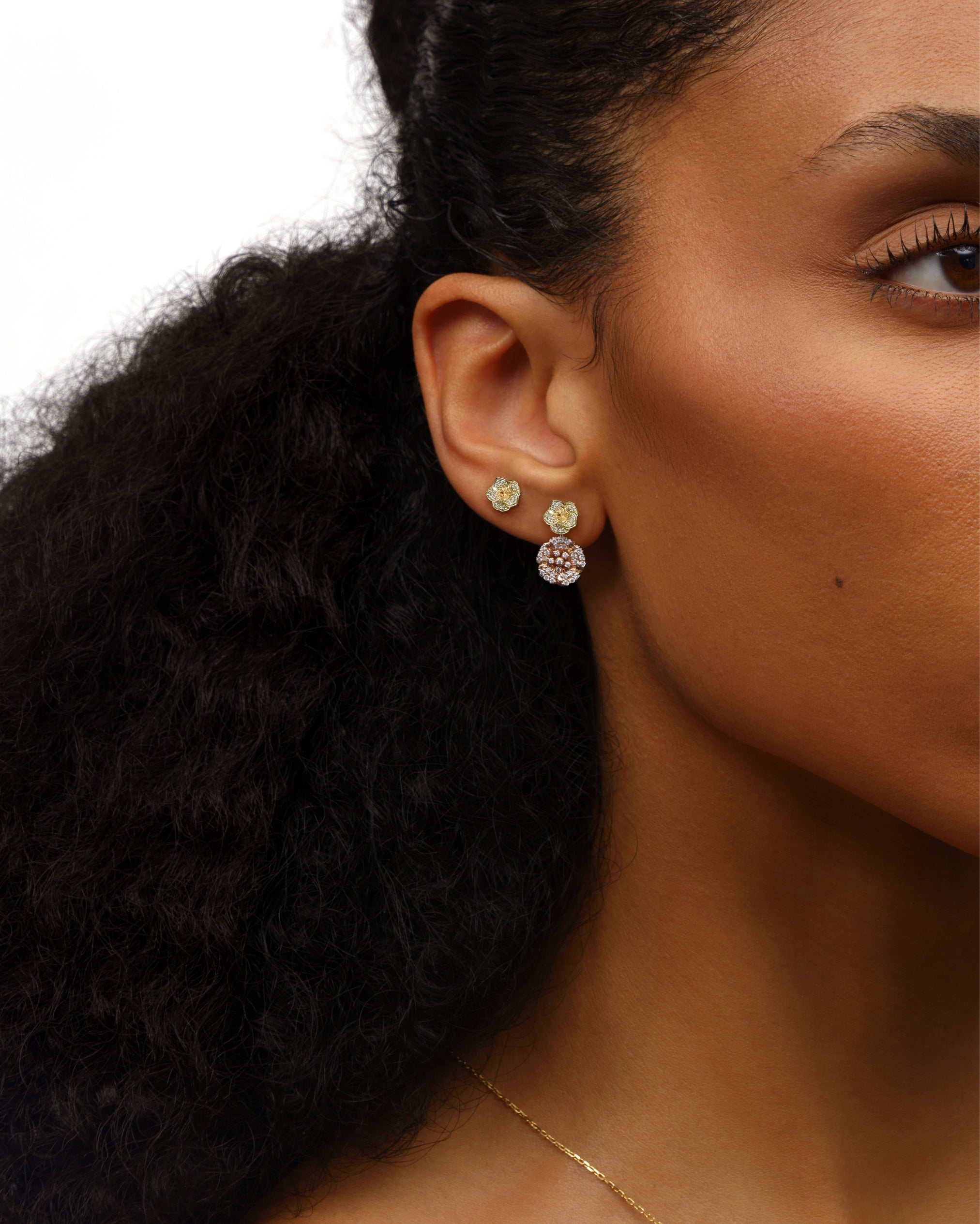 Close-up of a woman wearing gold earrings with a neutral background