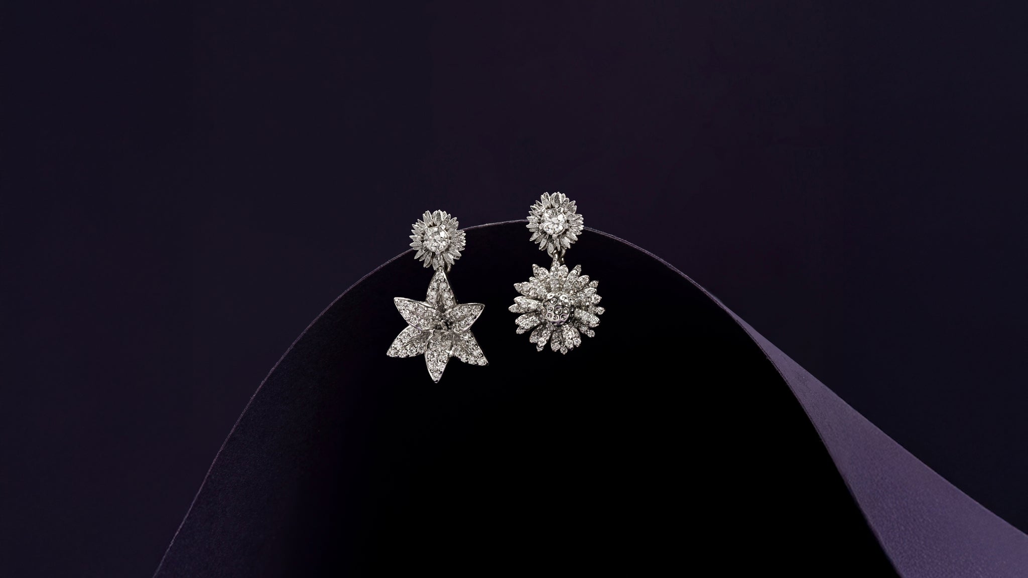 Pair of flower-shaped silver earrings on a dark background