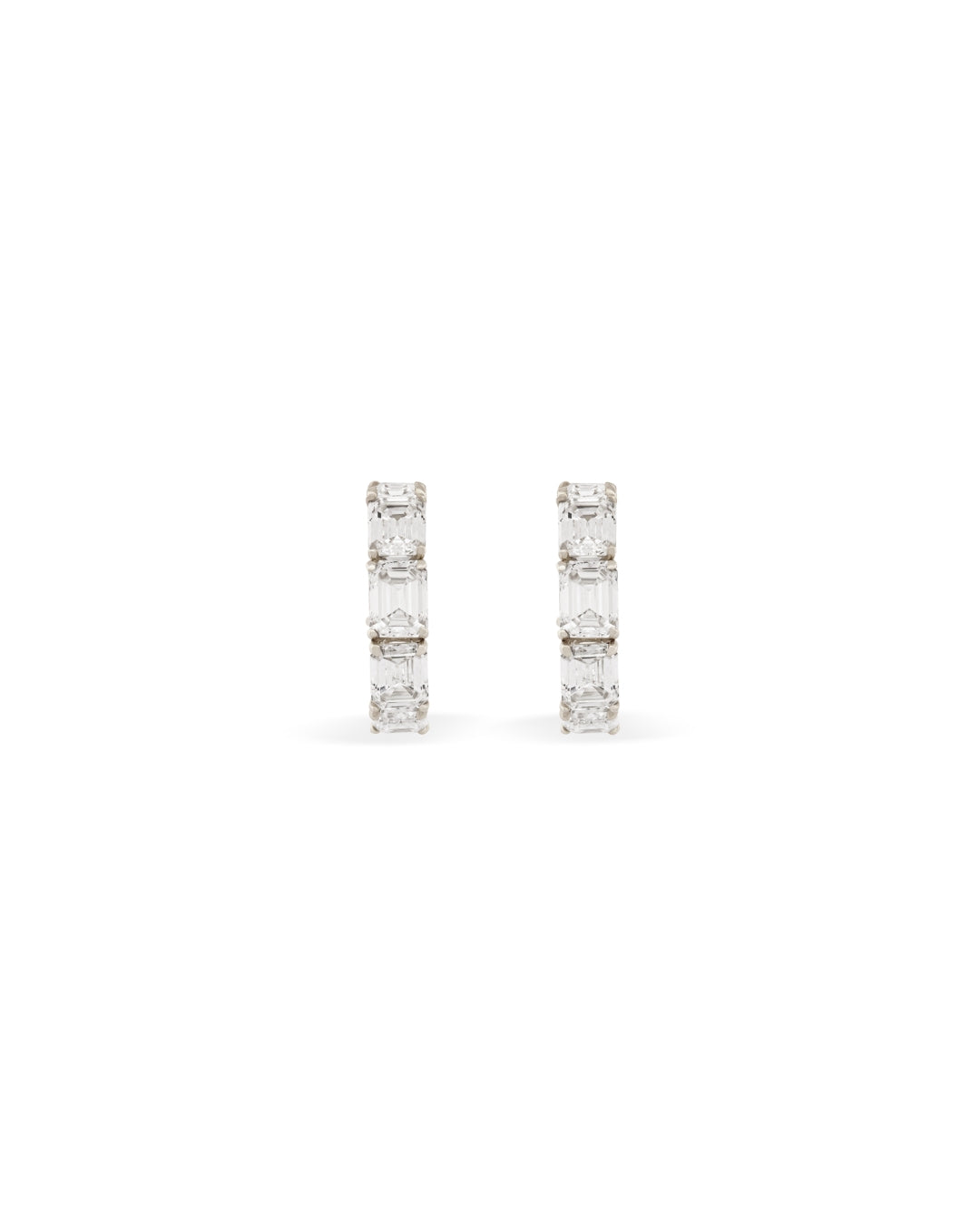 Small white gold diamond hoops with emerald cut white diamonds on a white background