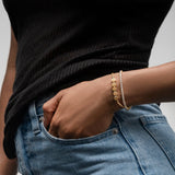 woman wearing a white diamond tennis bracelet and a 14k gold friendship bracelet with the letters AMICI