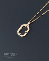 Gold necklace with a geometric pendant on a dark background