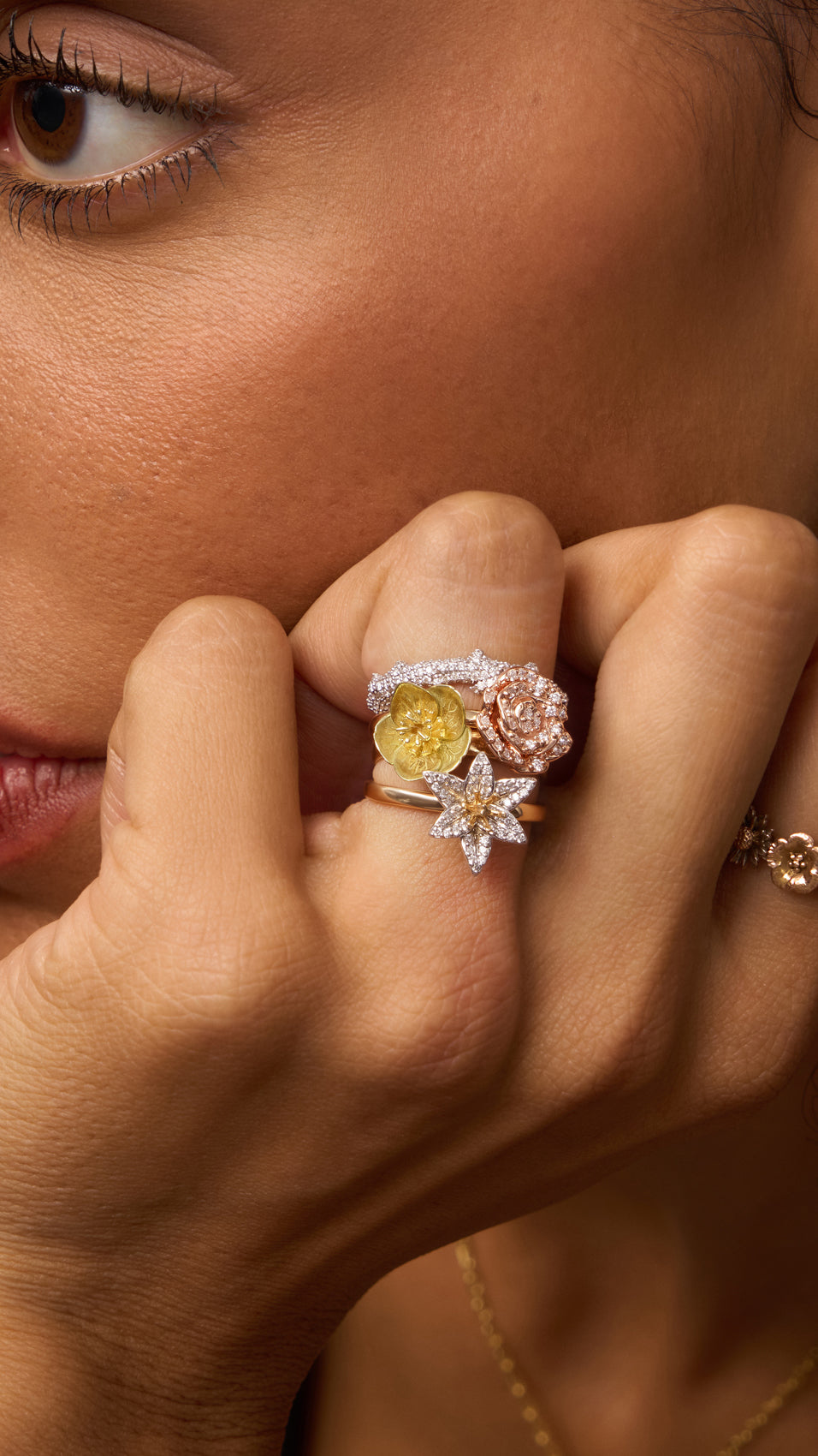 Close-up of a hand wearing two rings with yellow and pink gemstones.